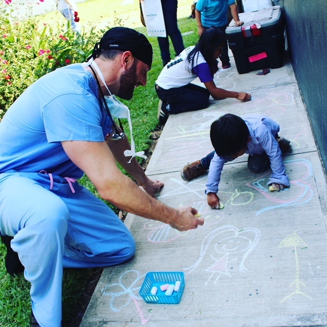 Dr. Justin Gusching draws with sidewalk chalk alongside Guatemalan children