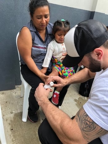 Dr. Justin Gusching wrapping a child's foot with gauze during a HELPS International medical mission trip in Guatemala